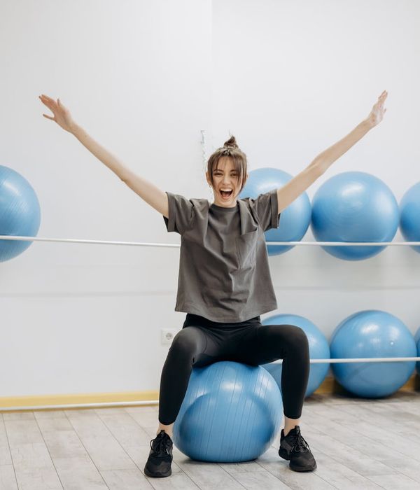 Woman stretching in a bright room, showing body flexibility.